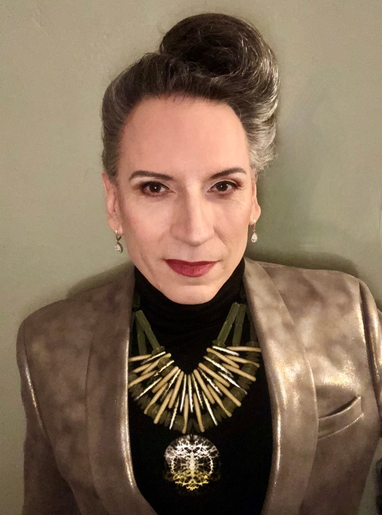 J. A. Valentine wearing a silver blazer, a necklace and with hair done up in a gorgeous swirl.